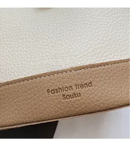 Gros plan sur le cuir grainé et logo embossé sur le sac seau bicolore en cuir