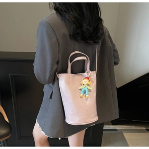 Detail view of a lavender bucket bag with a cute yellow cartoon doll charm accessory