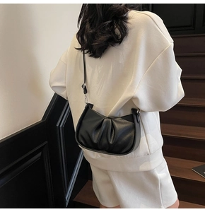 Detailed view of black crescent cloud bag with premium grain leather and pleat details