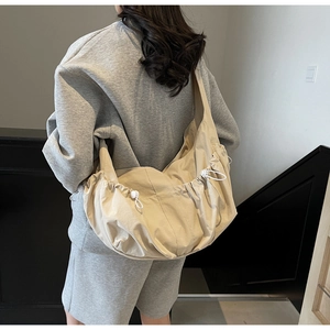 Detail of beige large canvas dumpling bag with adjustable drawstring on female model