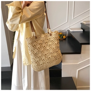Detailed weave of handmade straw tote bag featuring brown leather handle and wavy edge