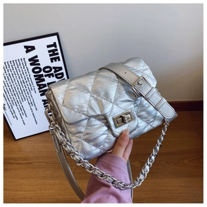 Macro shot of silver quilted puffer bag with metallic finish and twist-lock clasp detail