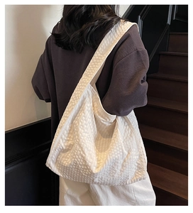 Detail shot of white waffle-textured canvas tote bag worn on shoulder by a model