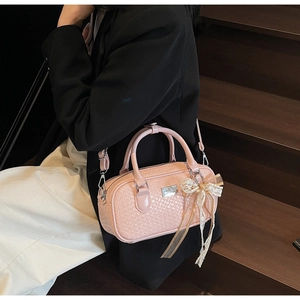 Dettaglio della trama rosa intrecciata della borsa Boston con ciondolo a fiocco in pizzo