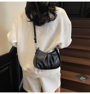 Detail of black cloud bag featuring pleated leather texture and adjustable strap
