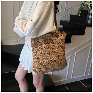 Detail of hand-woven hollow pattern on a khaki straw tote bag with brown leather strap