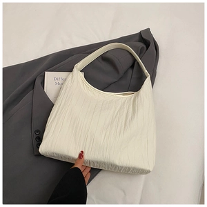 Vue détaillée de la texture plissée et de la large bandoulière du sac fourre-tout blanc crème