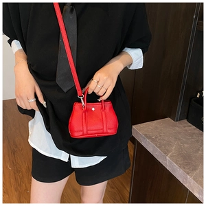 Detailed macro view of vibrant red mini bucket bag with silver metal lock and pebble leather