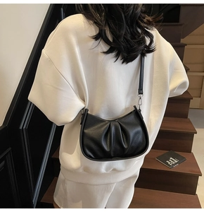 Close-up of black pleated dumpling bag with soft crescent shape and textured leather finish