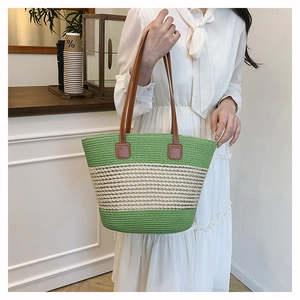 Dettaglio della borsa tote tessuta a righe verdi e beige con manici in pelle marrone