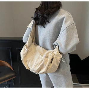 Detail view of beige crossbody dumpling bag with drawstring side pocket and canvas texture