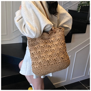 Detail of the woven texture and brown leather strap on the straw bucket shoulder bag