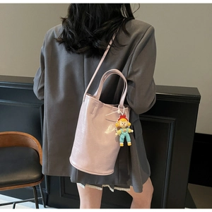 Detailed view of pink bucket bag with leather texture and cute cartoon doll pendant