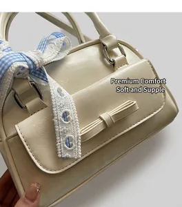 Detail of cream Boston bag featuring a leather bow and blue gingham ribbon accessory