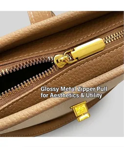 Détail de la fermeture éclair dorée et du cuir grainé sur un sac seau marron chic