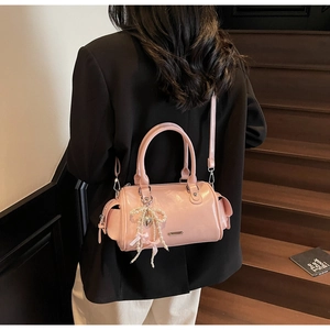 Dettaglio borsa Boston in pelle verniciata rosa con ciondolo di perle e tracolla