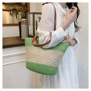 Dettaglio della borsa tote intrecciata verde con manico in pelle marrone su modella
