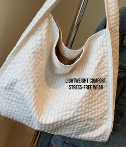 Detail view of large white quilted tote bag showing seersucker fabric and brown inner zipper
