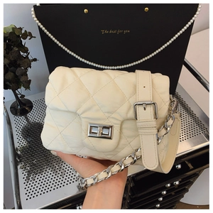 Detail of cream quilted crossbody bag with silver twist lock and chain strap
