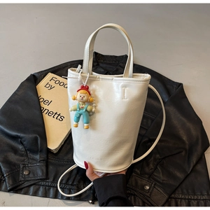 Macro detail of white pebble leather bucket bag featuring fashion embossing and doll charm