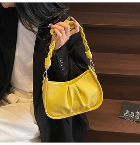 Close-up of bright yellow shoulder bag with pleated faux leather and woven handle