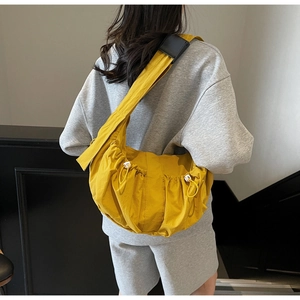 Detail of yellow nylon dumpling bag featuring adjustable drawstring and wide shoulder strap