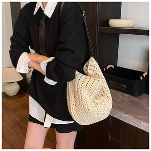 Detail of cream crochet woven bucket bag with contrast black leather shoulder strap
