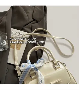 Detail of off-white leather Boston bag with blue checkered bow on lifestyle backdrop