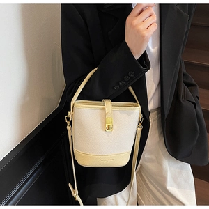 Détail du sac seau en cuir grainé avec fermoir rotatif doré et double bandoulière