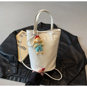 Detail of white bucket bag with textured leather, pearl chain and clown doll charm