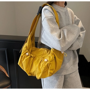 Detail of mustard yellow crossbody bag with drawstring pockets and wide shoulder strap