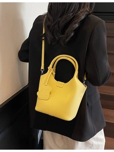 Bright yellow lychee grain leather bucket bag with puppy charm and adjustable strap