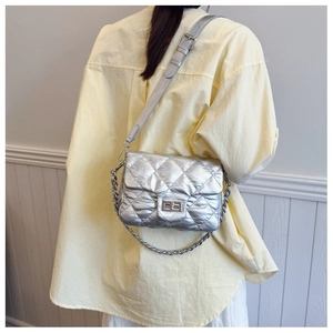 Detail of silver quilted crossbody bag with metal chain strap and turn-lock closure