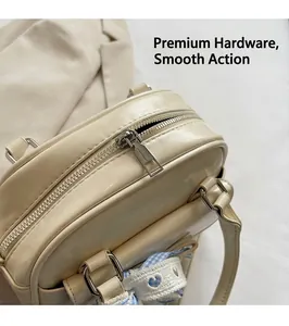 Close-up of smooth metal zipper and blue plaid ribbon on cream Boston handbag