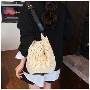 Close-up of cream woven bucket bag with black leather strap and textured crochet pattern