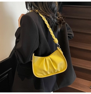 Detail of yellow pleated shoulder bag with lychee texture and braided strap