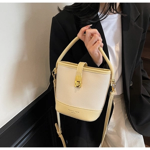 Détail du sac seau tendance en cuir texturé avec fermoir rotatif doré et design élégant