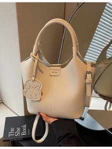 Elegant cream bucket bag with lychee texture, featuring top handle and cute dog charm