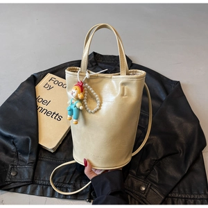 Detail of beige bucket bag featuring a fashion stamp and a pearl charm accessory