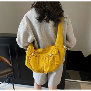 Detail of ginger yellow crossbody bag with adjustable drawstring and wide shoulder strap