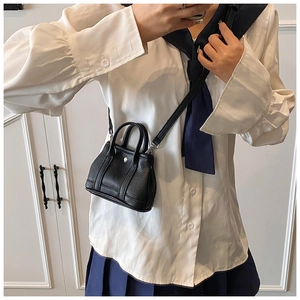 Close-up of small black lychee leather bucket bag with top handles and shoulder strap