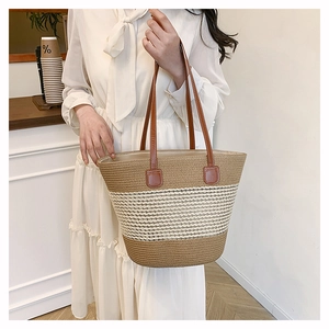 Dettaglio di una grande borsa tote in paglia intrecciata con manici in pelle