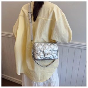 Close-up of silver quilted crossbody bag with metal chain strap and turn-lock closure