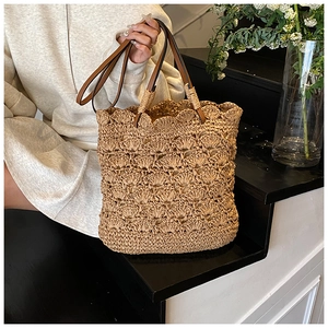 Detail of hand-woven straw bucket bag with scallop edge and brown leather strap