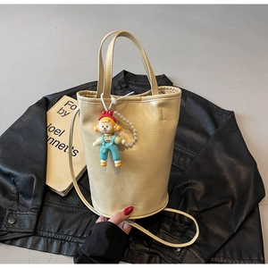 Detail of cream bucket bag with lychee leather texture and pearl doll charm on leather