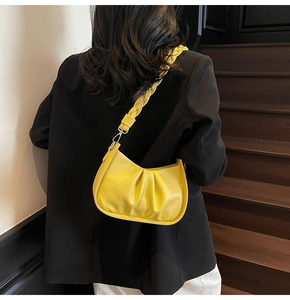 Detail of lemon yellow hobo bag featuring pleated leather texture and braided shoulder strap