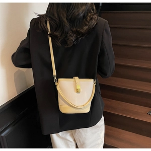 Détail du sac seau blanc crème avec cuir grainé et boucle dorée porté par un mannequin