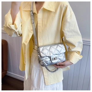 Close-up of a silver quilted crossbody bag with a metal turn-lock and chain strap