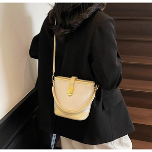 Sac seau en cuir litchi beige avec fermoir doré rotatif et bandoulière de messager