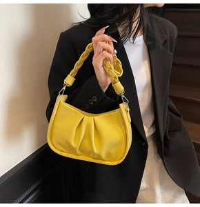 Detailed view of yellow pleated dumpling bag with thick woven handle and leather texture